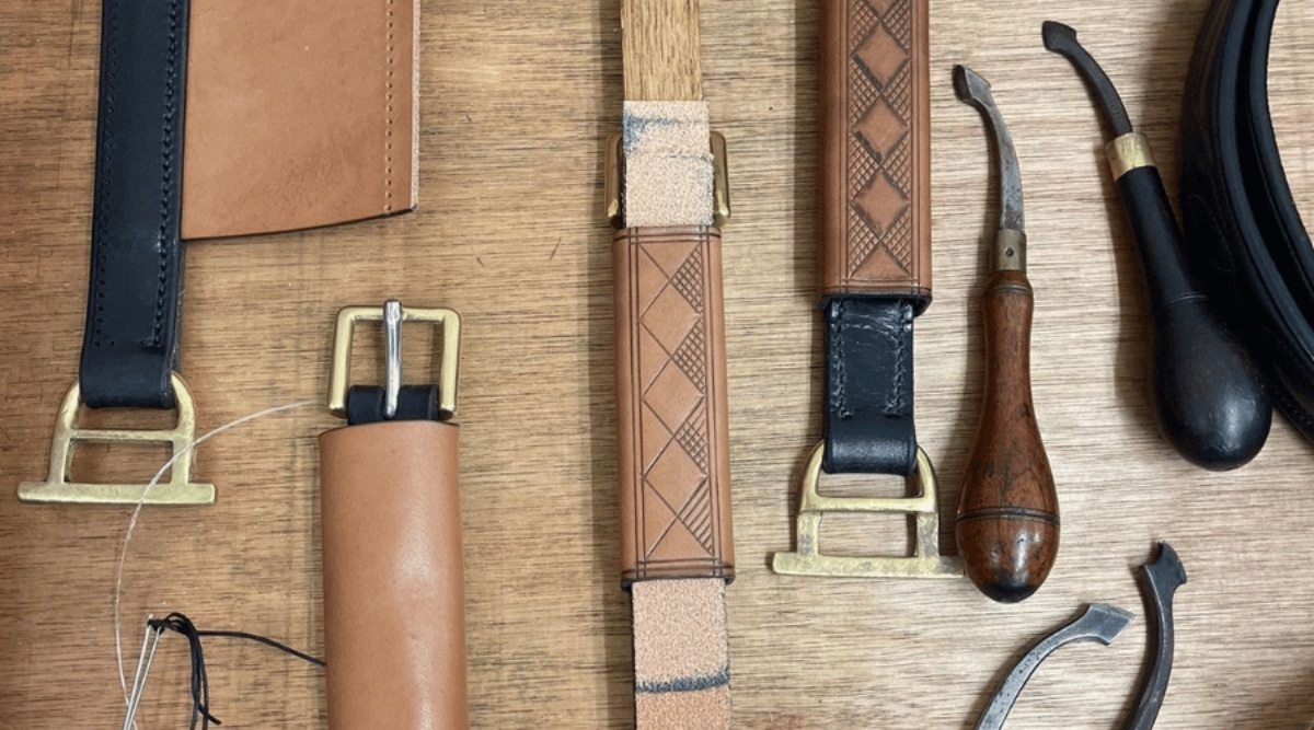 A image of boxloops in various stages of completion at the Walsall Leather Skills Centre along with leather working tools such as edgers, waxed thread and metal buckles and hardware. The boxloops are decorated.