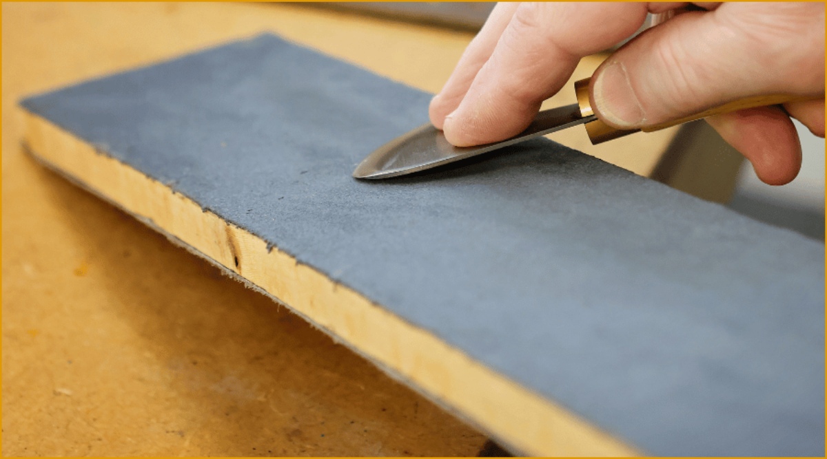 A tutor at the tools maintenance and sharpening course preparing a saddlers round knife at the Walsall Leather Skills Centre on a sharpening block.