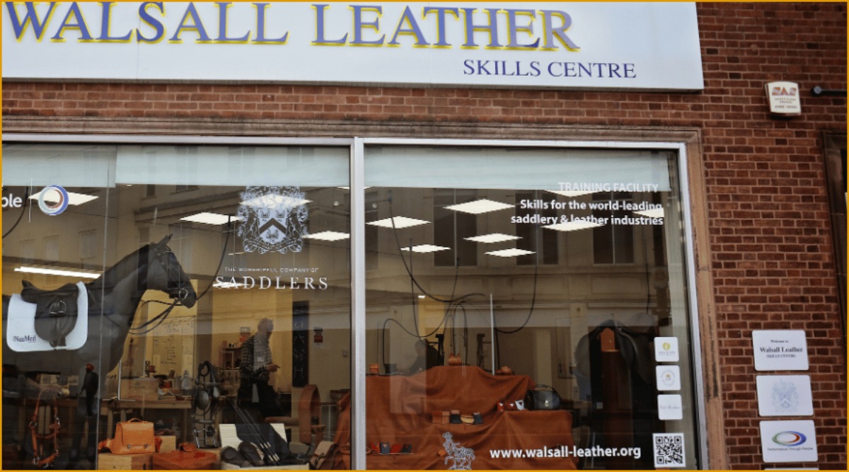 The shop front of the Walsall Leather Skills Centre, showing the leather display in the window and a horse wearing tack. The ‘Saddles Company’ crest is visible on the window and various other leather organisational branding.