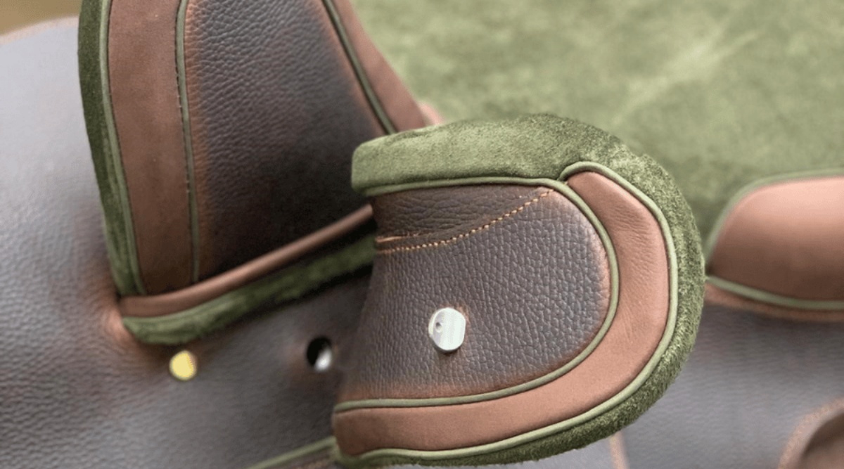 A close up of a side saddle fixed head and leaping head, with green and brown leather, created at the walsall leather skills centre side saddle construction course.